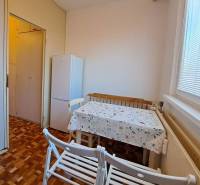 Dining room in a 2-room apartment with a wood-patterned floor and a white refrigerator.