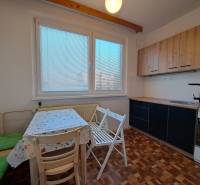 A kitchen in a 2-room apartment with a wooden decor floor and a dining area.