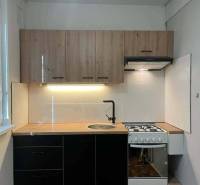 A kitchen in a 2-room apartment with a wooden cabinet and a panel floor.
