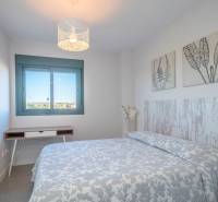 A bedroom in a 2-room apartment with a patterned blanket and decorations on the walls.