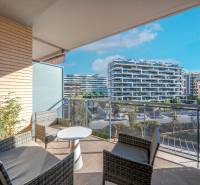 Balcony of a 2-bedroom apartment in Alicante with outdoor furniture and a view of modern buildings.