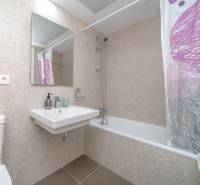 A bathroom in a 2-room apartment with modern tiles, a bathtub, and a sink.
