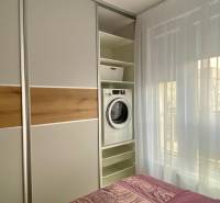 Bedroom in a 2-room apartment with a washing machine in a built-in closet and a bed.