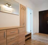 Hallway in a 3-room apartment with a wooden decor floor and wooden furniture.