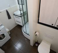 Bathroom with a washing machine, shower, and toilet in a 3-room apartment.