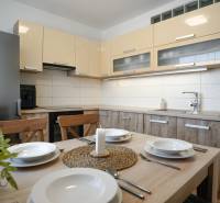 A kitchen in a 3-room apartment with a furnished dining area and a wooden decor floor.