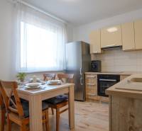 A kitchen in a 3-room apartment with a wooden decor floor, wooden table and chairs.