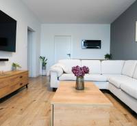 Living room in a 3-room apartment with a white couch, wood-patterned flooring, and decorations.