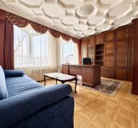 A room in a 4-room apartment with a comfortable sofa, a work desk, and a floor with a wooden decor.