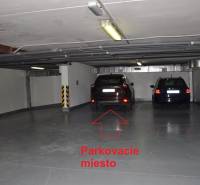 Underground garage with parked cars and a free parking spot marked with a red arrow.
