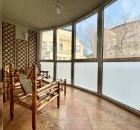 A typical winter garden for a 4-room apartment features rattan furniture and large windows.