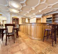 A kitchen in a 4-room apartment with a dining table, wooden furniture, tiles, and an interesting ceiling.