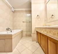 Bathroom in a 4-room apartment with a bathtub, shower corner, marble tiles, and a sink.