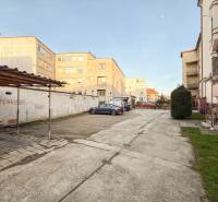 Parking lot near 2-room apartments on Hodžova Street in Trenčín with cars and greenery.