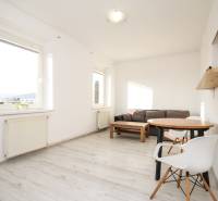 White interior in a 2-room apartment with a sofa, table, and wood-patterned floor.