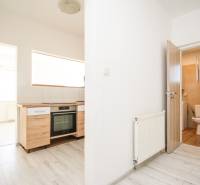 A kitchen in a 2-room apartment with a wooden decor floor and a bathroom.