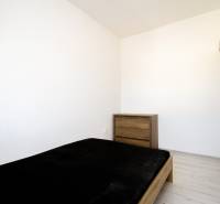Bedroom in a 2-room apartment, contains a bed, a dresser, and a floor with a wooden decor.