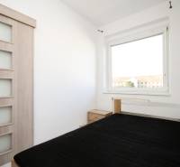 A bedroom in a 2-room apartment with a bed and a wardrobe by the window.