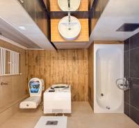 Bathroom with a bathtub, sink, washing machine, and floor with wooden decor in a 2-room apartment.