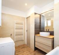 Bathroom in a 2-room apartment with a sink, mirror, washing machine, and floor with wooden decor.