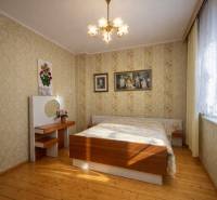 A bedroom in a family house with a wood-patterned floor and floral wallpaper.