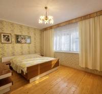 A bedroom in a family house with wallpaper, wooden decor, and chandeliers.