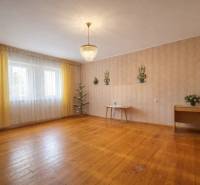 Interior of a family house with wood-patterned flooring, a chandelier, and decorative wallpaper.