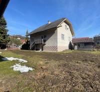 A family house in Terchová with a large yard and a shelter, surrounded by grass and trees.