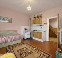 A room with a kitchen unit, sofa, stove, and wooden decor flooring in a family house.