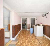 A hallway in a family house with a wooden decor floor, cabinets, and doors leading to the bathroom.