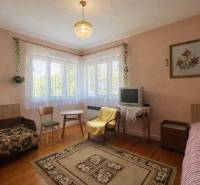Living room in a family house with a carpet, television, and wooden decor flooring.