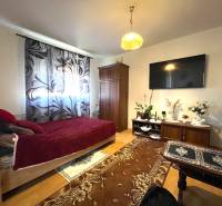 A one-room apartment with a bed, a television, and a floor with a wooden decor.