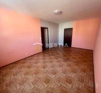A room in a 3-room apartment with pink walls and a wooden decor floor.