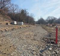 Lands - housing in Haniska, a rocky road between trees and a container.