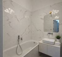 A bathroom with a bathtub, sink, mirror, and decorative light fixture in a 3-room apartment.