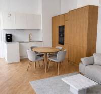 A kitchen in a 3-room apartment with a wood-patterned floor, a gray carpet, and a dining table.