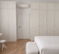 Bedroom with white wardrobes, bed, wood-decorated flooring, and air conditioning in a 3-room apartment.