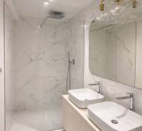 A bathroom in a 3-room apartment with white ceramic tiles and two sinks.