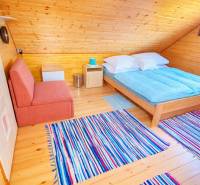 Attic cabin with a bed, sofa, wooden decor flooring, and striped carpet.