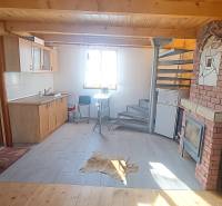 A cottage with a kitchen, spiral staircase, and wood-patterned flooring.