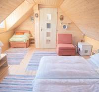 Wooden interior of the cabin with a wood-patterned floor, bed, and chair.