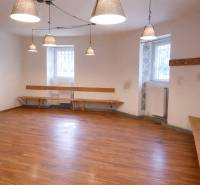 Commercial space with wood-patterned flooring, benches, and hanging lamps.