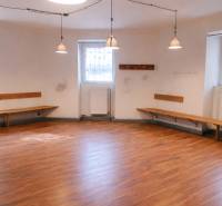 Commercial space with walls, benches, and floor with wooden decor, illuminated by pendant lamps.
