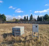 Building plot in Nové Zámky with concrete blocks and an instrument box, surrounded by greenery.