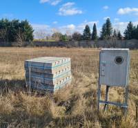 Building plot in Nové Zámky with concrete paving and an electrical cabinet.