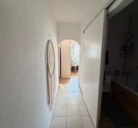 A hallway with tiles in a 3-room apartment with wall decorations and a view into the bathroom.
