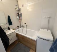 Bathroom in a 3-room apartment with a bathtub, sink, and washing machine, white tiles.