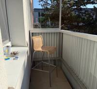 A balcony in a 3-room apartment with a bar stool and items on the windowsill.