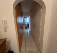 A hallway with light tiles, an arched passageway, and a wardrobe in a 3-room apartment.