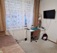 A room in a 4-room apartment with a table, bed, and television, floor with wooden decor.